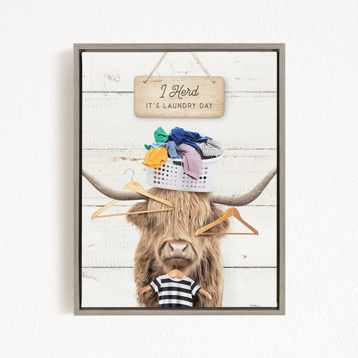 A framed image depicting a cow with a sign above it that says "I herd it's laundry day", and a basket of clothes on its head.