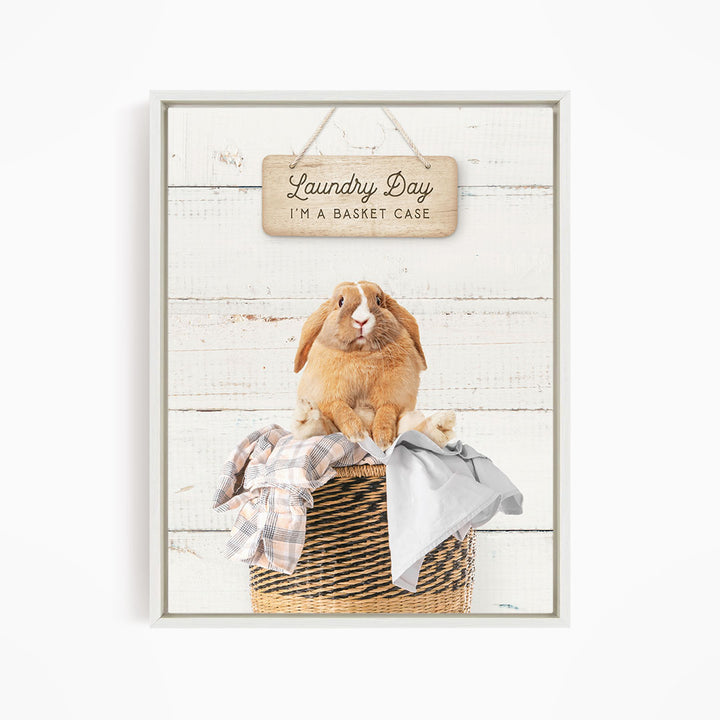 A wooden sign with the text "Laundry Day I'm a basket case" hangs above a woven basket containing clothes and a small rabbit.