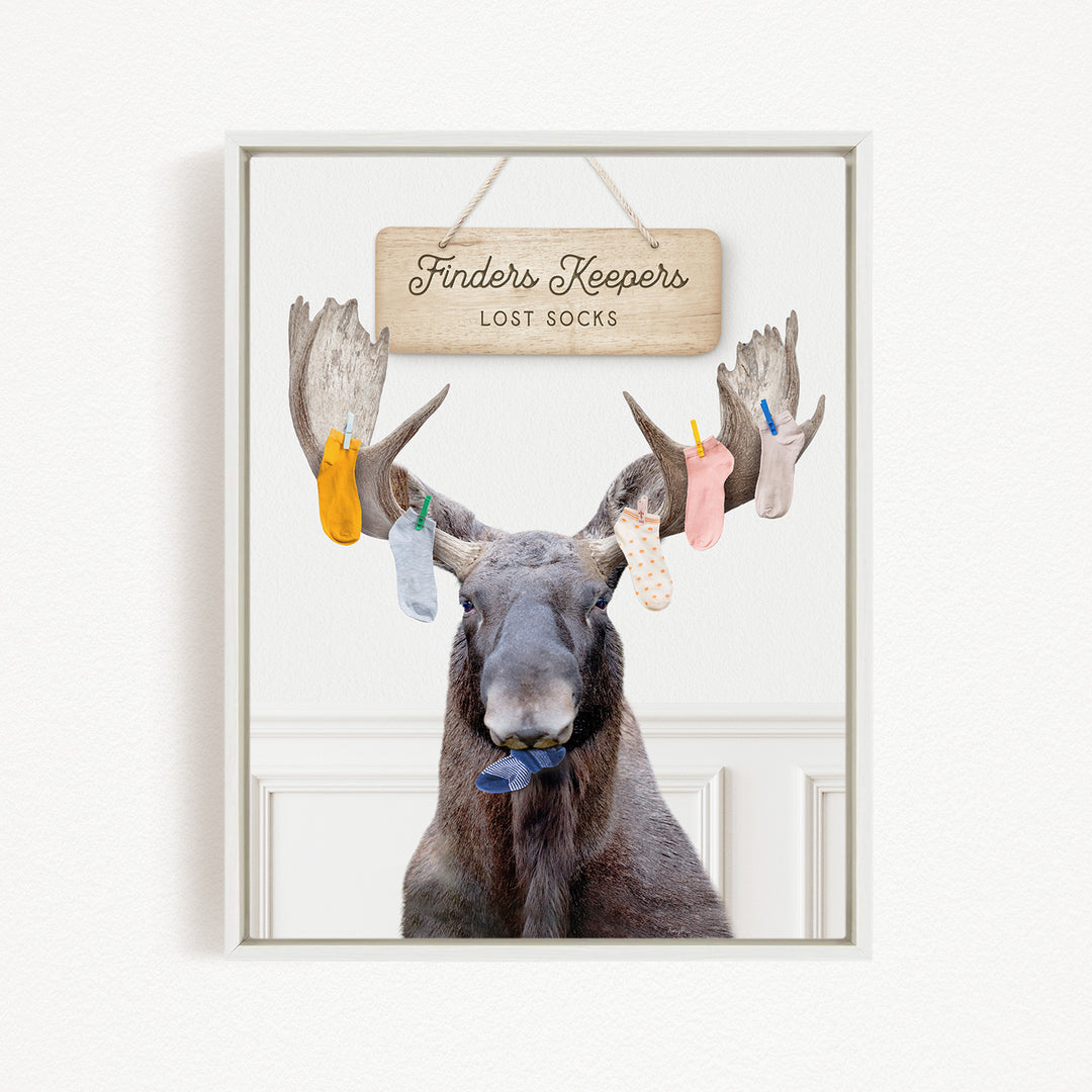 A framed image of a moose with a sign above it that says "Finder's Keepers Lost Socks".