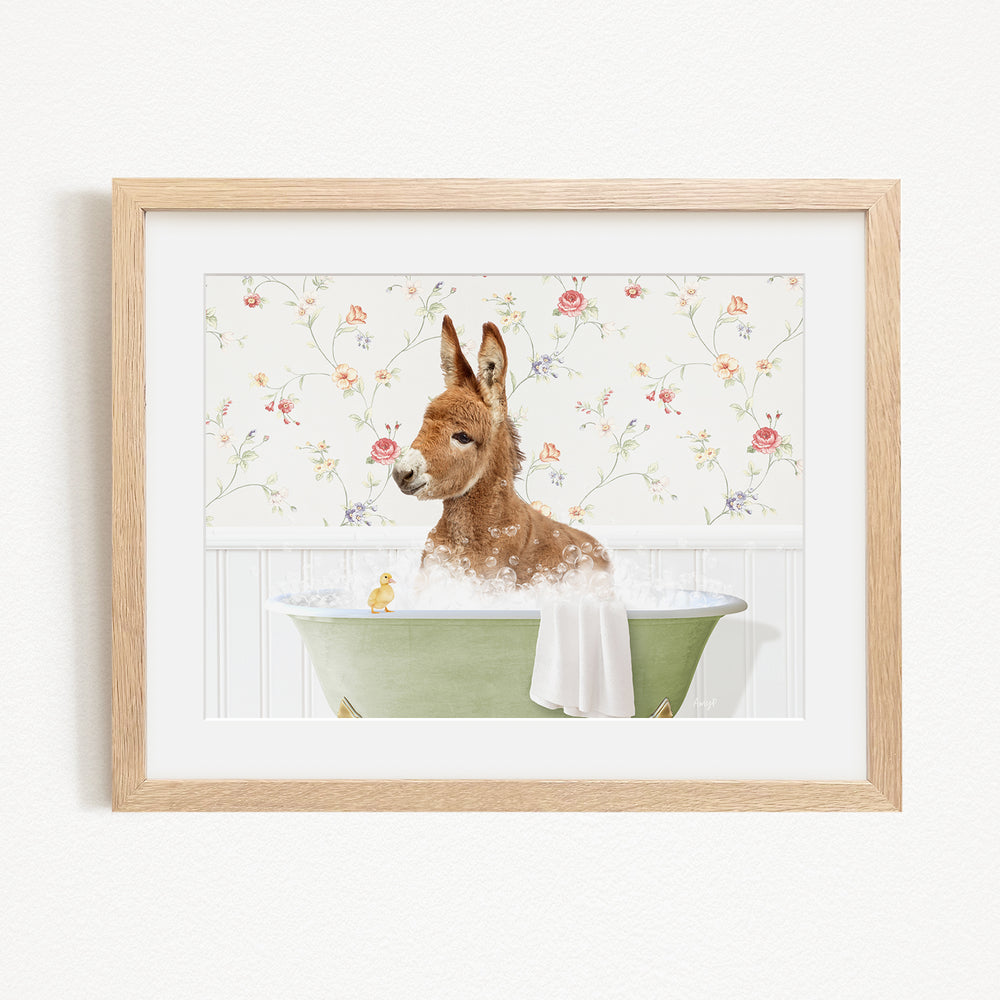 A brown alpaca is sitting in a green bathtub filled with water, surrounded by a floral pattern on the wall behind it.