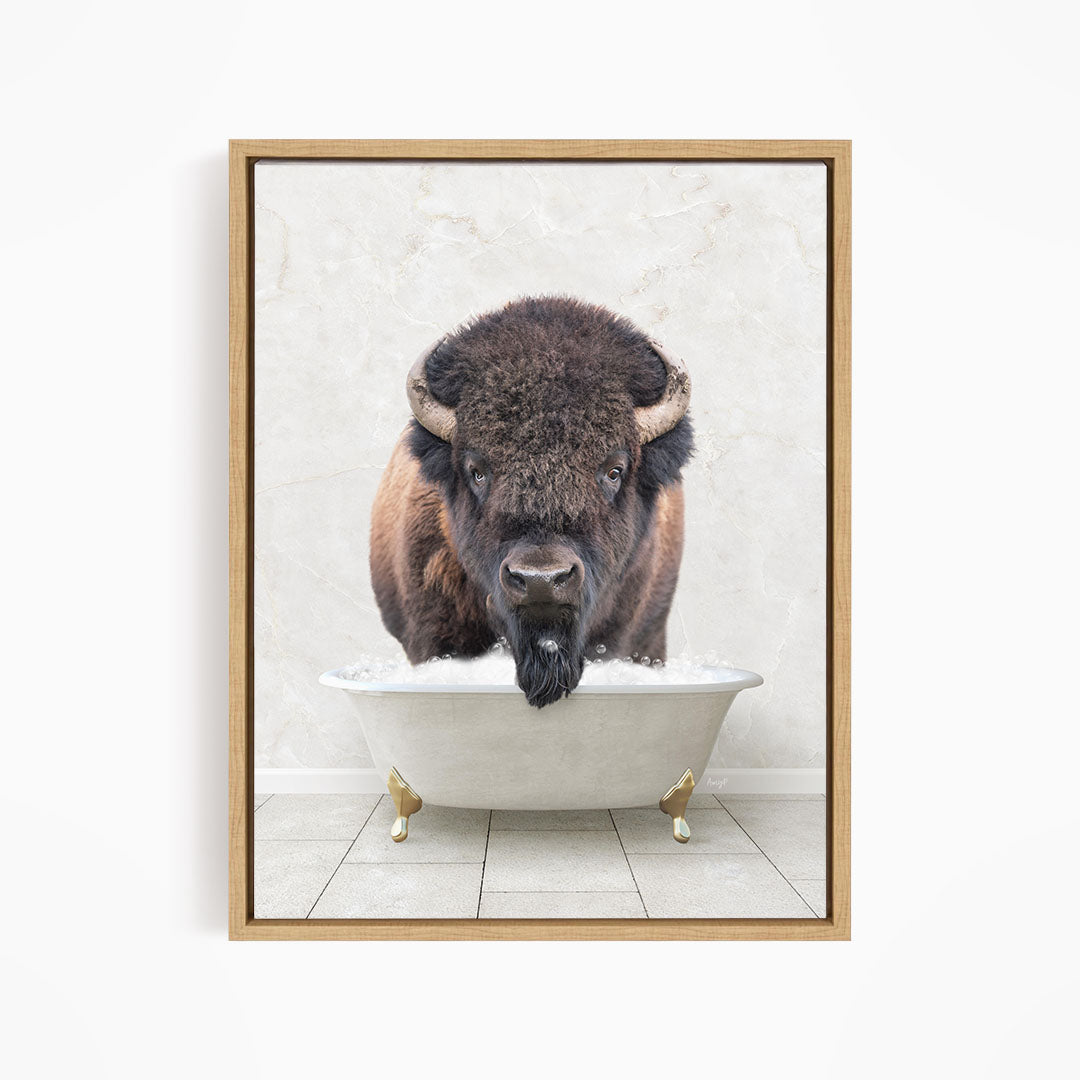 A buffalo with large horns is standing in a white bathtub, appearing to be enjoying a bath.