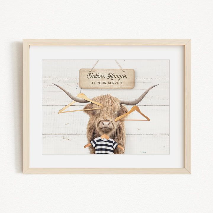 A framed image depicting a large, furry animal with a sign that reads "Clothes Hanger at your service" in front of it.