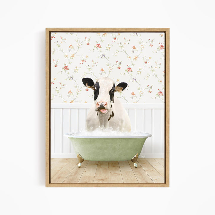 A black and white cow is sitting in a green bathtub filled with water, with a floral wallpaper in the background.