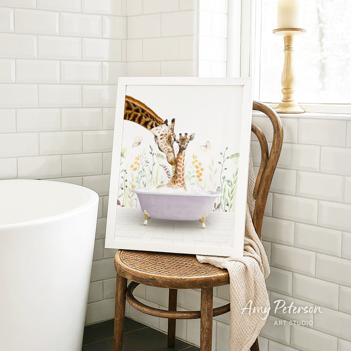 A framed painting of two giraffes sitting in a bathtub, surrounded by flowers, is displayed on a wooden chair in a bathroom setting.