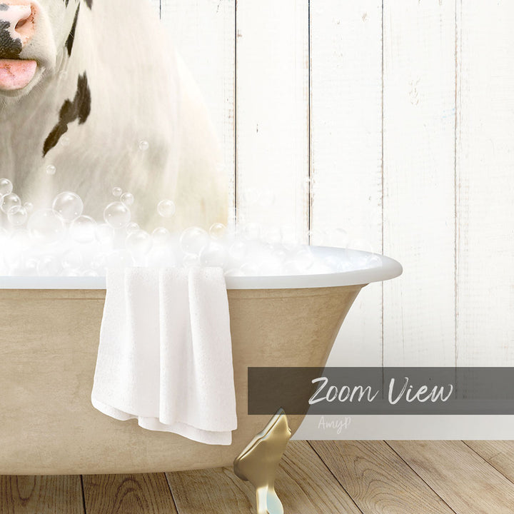 A white cow is sitting in a bathtub filled with bubbles, with a towel draped over the side of the tub.
