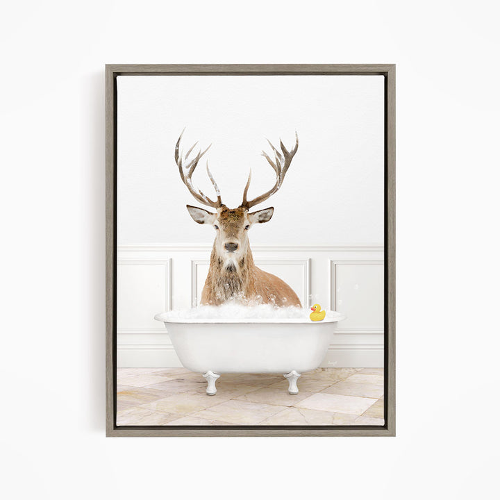 A deer with large antlers is sitting in a white bathtub filled with water, with a rubber duck floating in the tub.