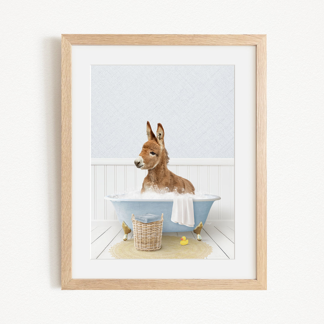 A donkey is sitting in a blue bathtub filled with water, surrounded by rubber ducks.