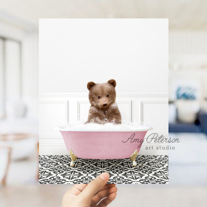 a small teddy bear sitting in a pink bath tub