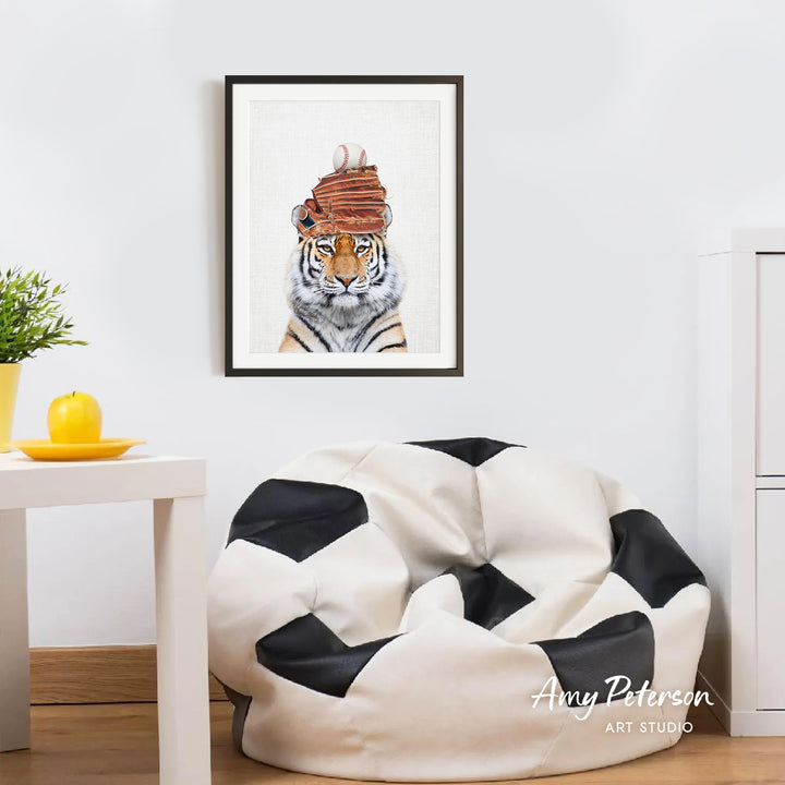 a tiger wearing a hat with a baseball on top, which is hanging on a wall above a white bean bag chair.