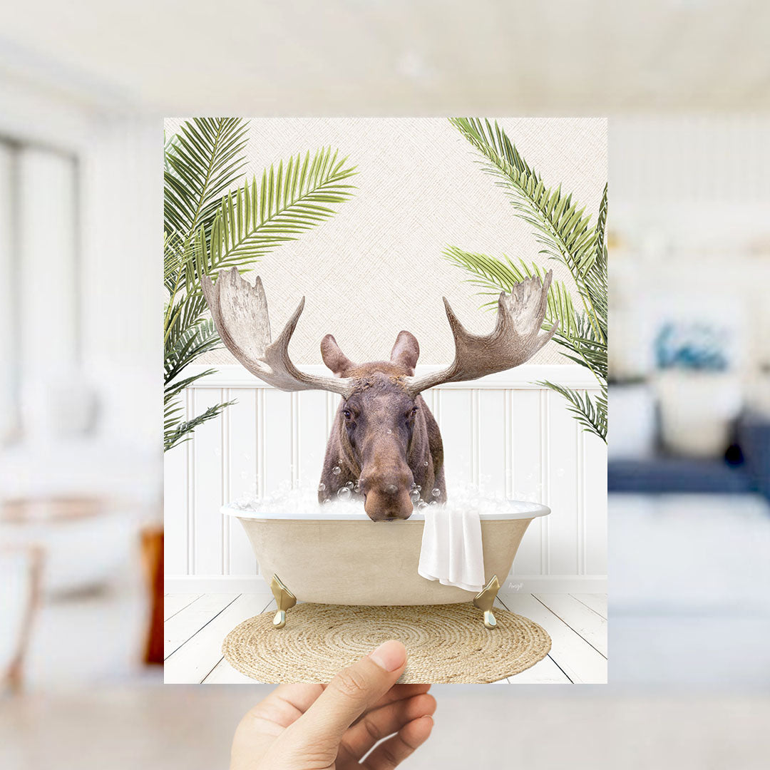 A moose with large antlers is sitting in a bathtub filled with water, surrounded by green leaves.