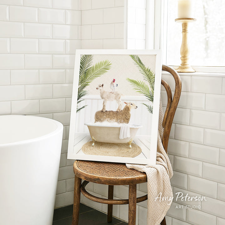 A framed image of a sheep standing on a bathtub, surrounded by palm leaves, is displayed on a wooden chair in a bathroom setting.
