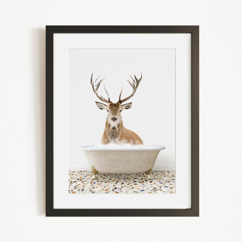 A deer with large antlers is sitting in a white bathtub filled with water, creating a whimsical and unexpected scene.