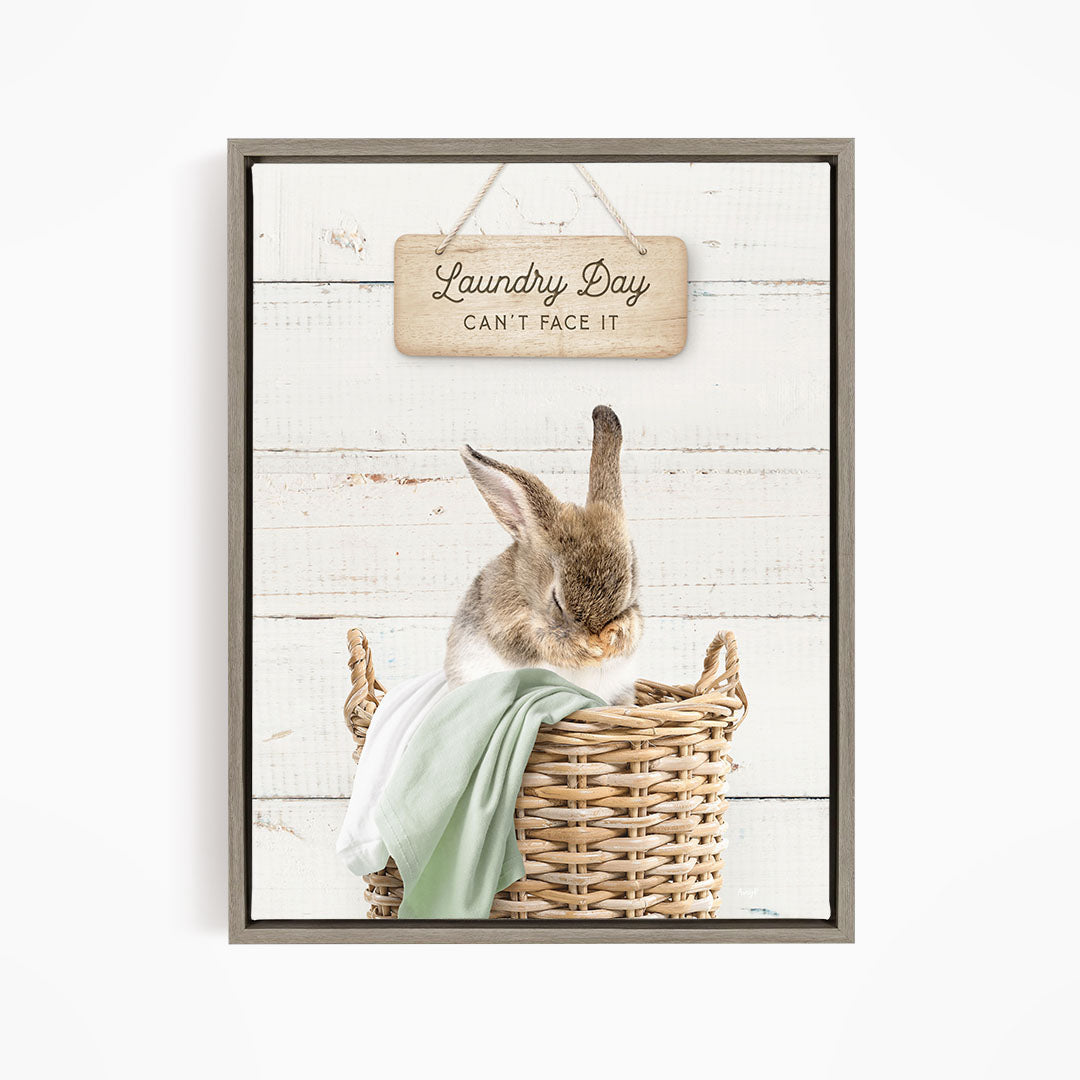 A cute rabbit sitting in a wicker basket, with a wooden sign above that says "Laundry Day Can't Face It".