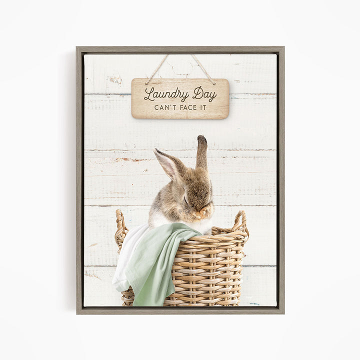 A cute rabbit sitting in a wicker basket, with a wooden sign above that says "Laundry Day Can't Face It".