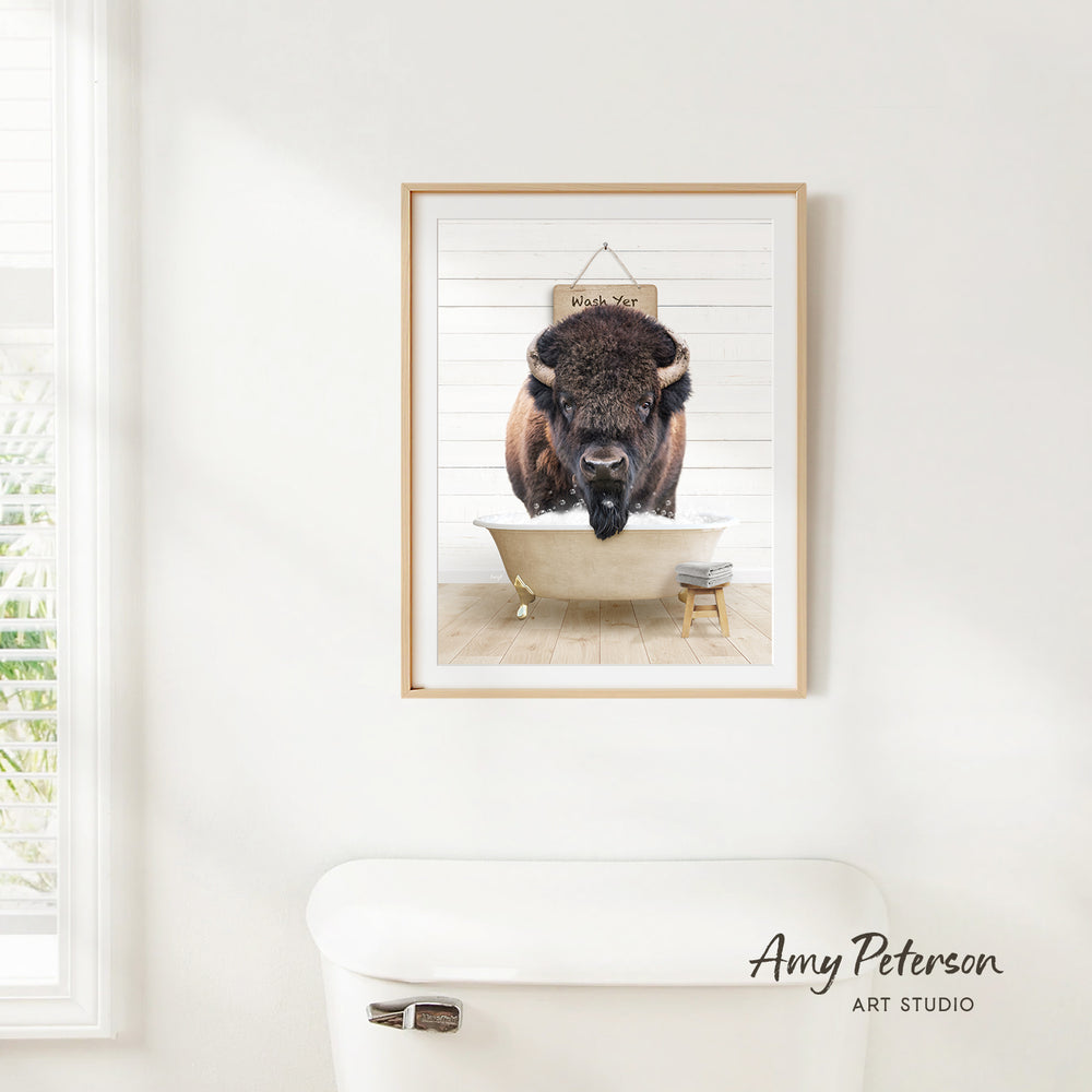 A framed image of a buffalo resting in a bathtub, with a sign above it that says "Wash Your Bison".
