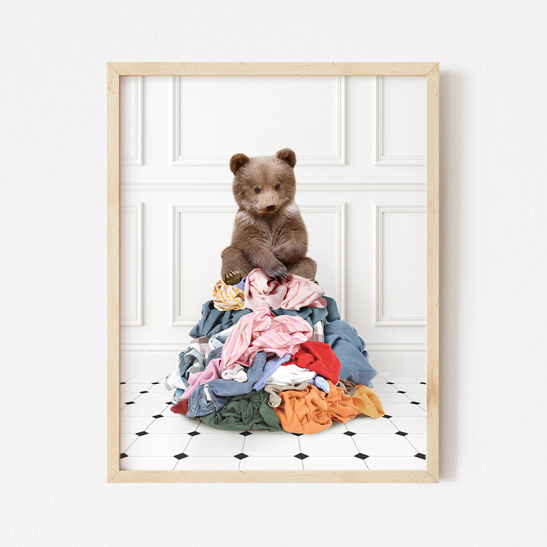 a brown teddy bear sitting on top of a pile of clothes