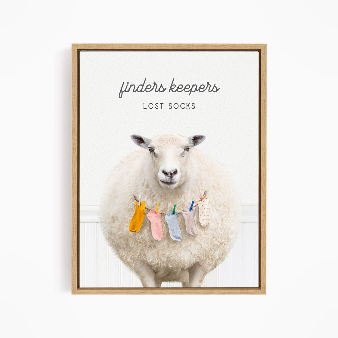 A white sheep standing in front of a white wall, with a pile of colorful socks hanging from a clothesline in front of it.
