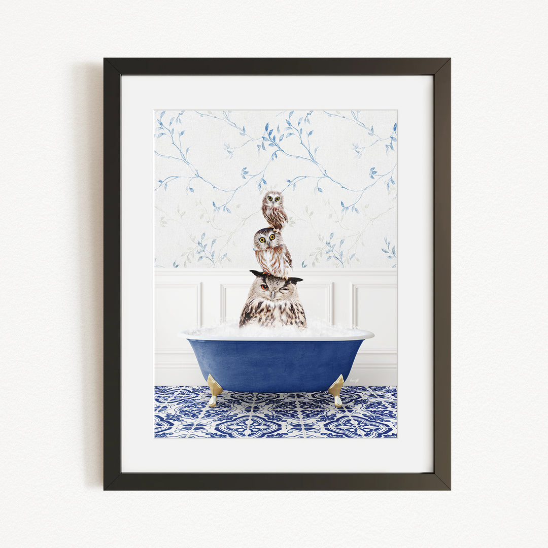 A framed image depicting a group of owls sitting in a blue bathtub, with a patterned tile floor and a floral wallpaper in the background.