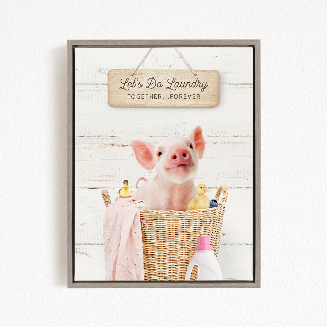 A cute pig sitting in a wicker basket filled with various toys, including a yellow duck and a pink blanket, with a sign that says "Let's Da Laundry Together Forever" hanging above.