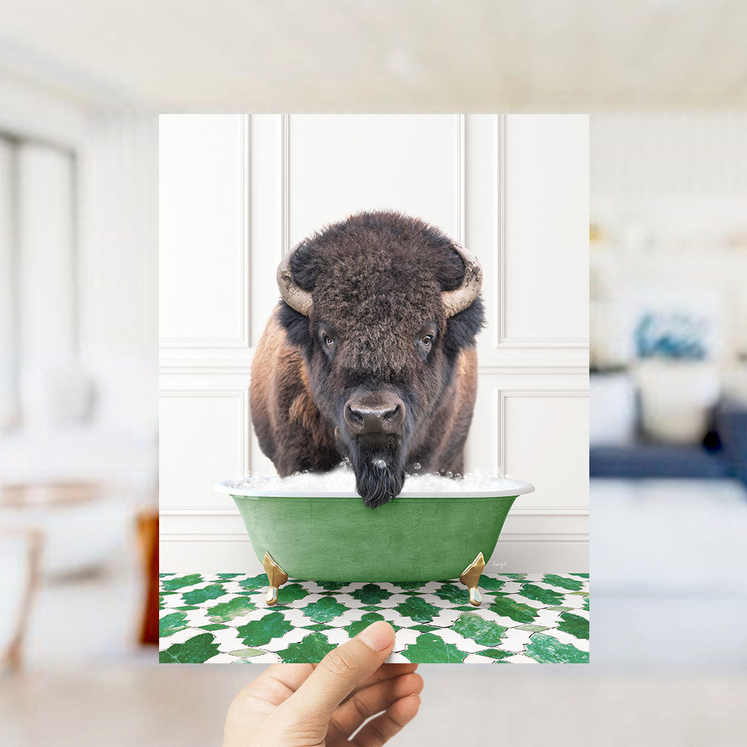 A large bison with horns is sitting in a green bathtub filled with water, with a hand holding the image up to the viewer.