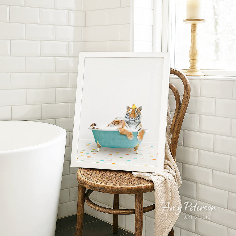 A framed image of a tiger sitting in a bathtub, surrounded by colorful tiles, is displayed on a wooden chair in a bathroom setting.