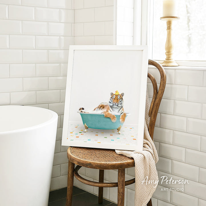 A framed image of a tiger sitting in a bathtub, surrounded by colorful tiles, is displayed on a wooden chair in a bathroom setting.