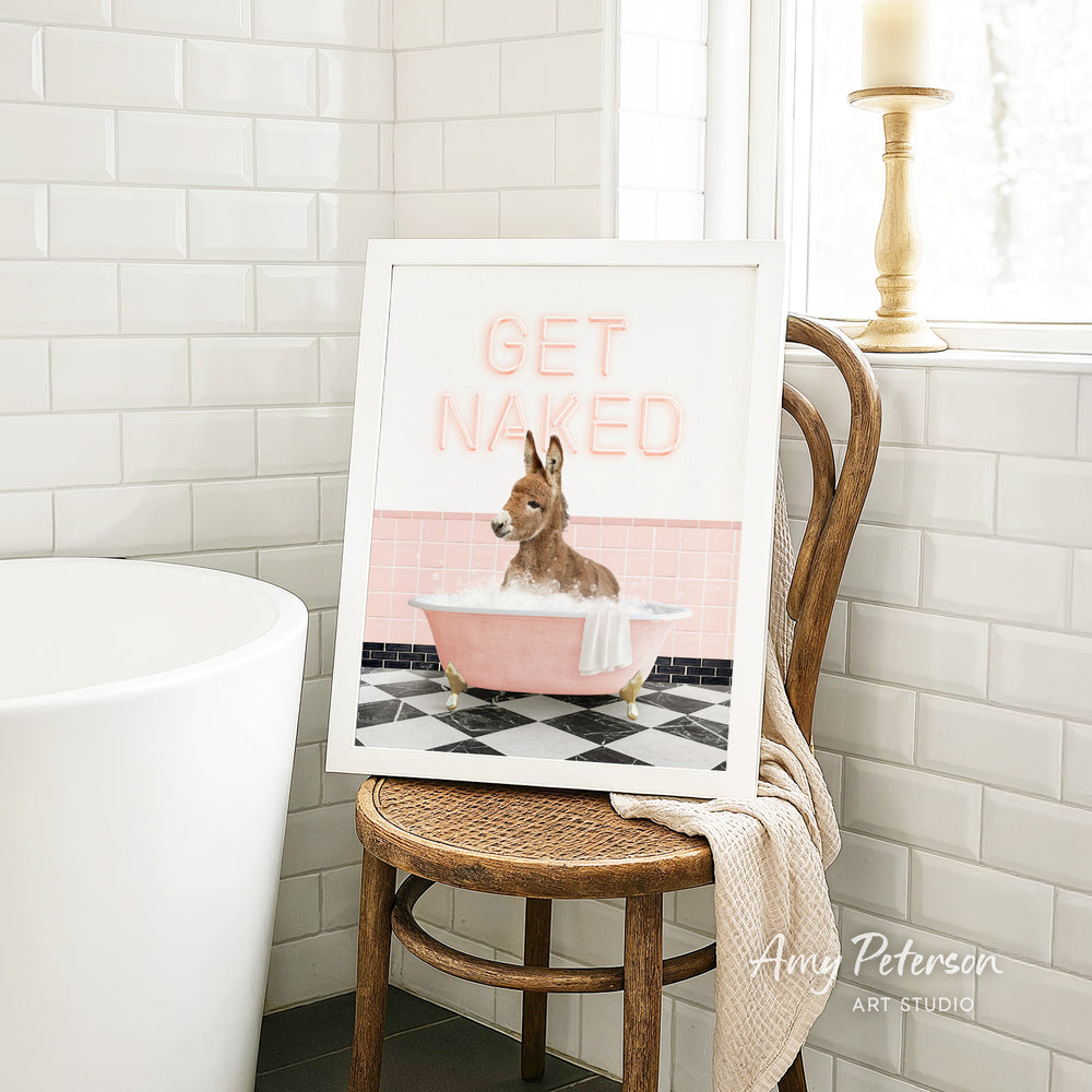 A framed image of a dog sitting in a pink bathtub, with the text "GET NAKED" displayed on the frame.