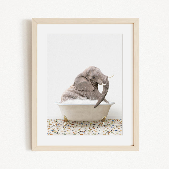 A gray elephant sitting in a white bathtub filled with water, with its trunk submerged in the water.