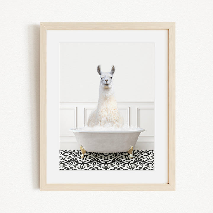 A white llama sitting in a white bathtub filled with bubbles, with a black and white patterned floor in the background.