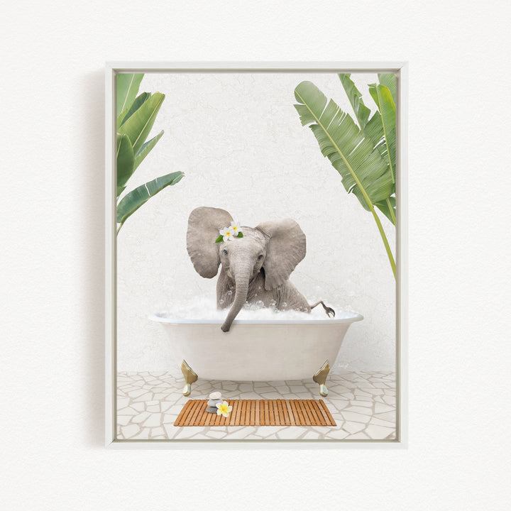 A gray elephant is sitting in a white bathtub filled with water, surrounded by green leaves and a wooden mat on the floor.