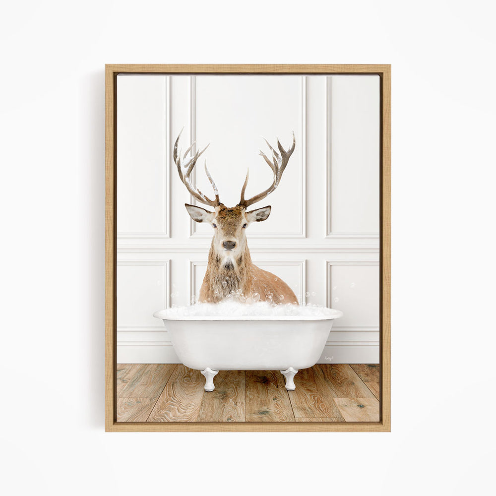 A deer with large antlers is sitting in a white bathtub, surrounded by a white wall and wooden floor.