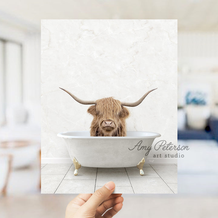 a hand holding up a photo of a bull in a bathtub