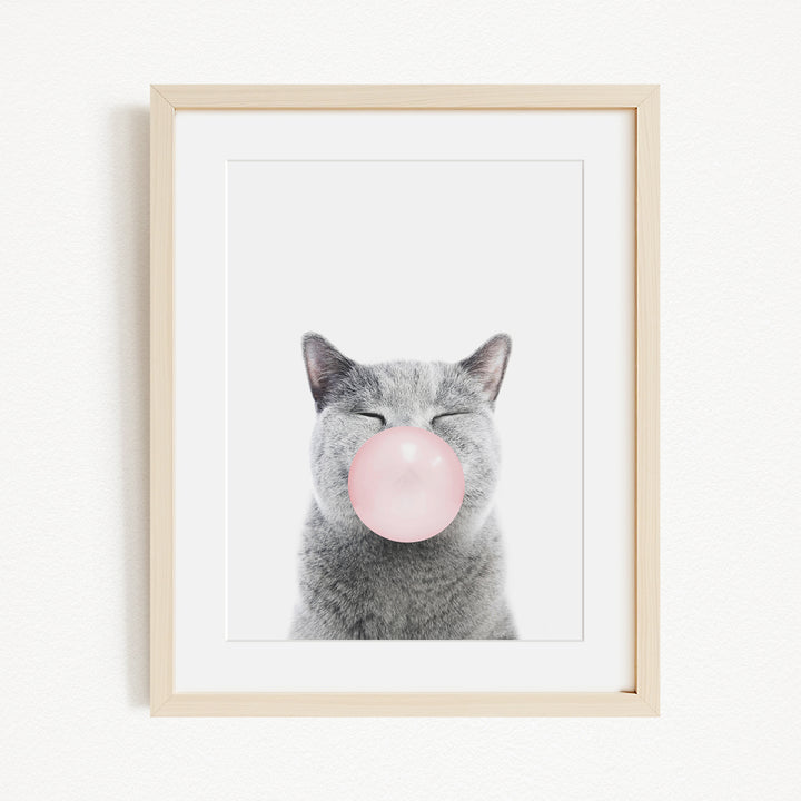 A gray cat with its eyes closed and a pink bubble blowing in its mouth, creating a whimsical and playful scene.