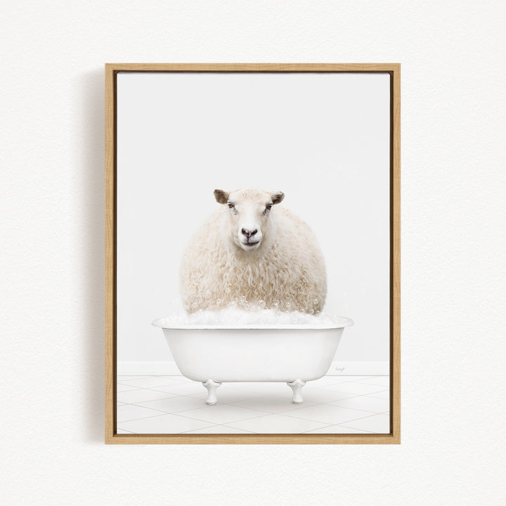 A fluffy white sheep sits in a white bathtub filled with bubbles, looking directly at the camera.