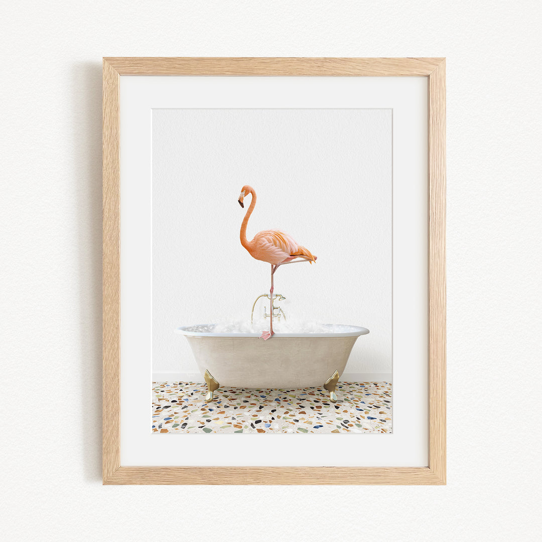 A framed image of a flamingo standing in a white bathtub filled with water.