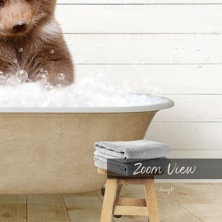 A brown bear is sitting in a bathtub filled with bubbles, with a towel and stool nearby.