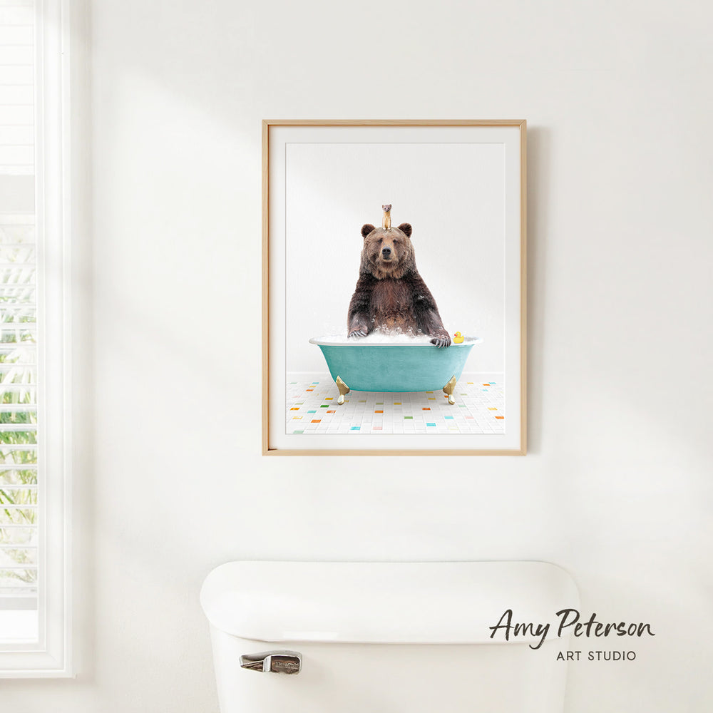 A framed image of a bear sitting in a bathtub filled with water and bubbles, with a window and toilet visible in the background.