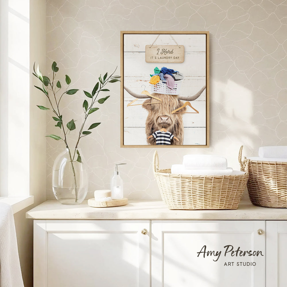 a framed picture of a cow with clothes on its head, hanging on a wall above a white cabinet with baskets.