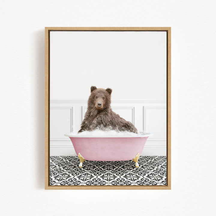 A brown bear sitting in a pink bathtub filled with bubbles, surrounded by a black and white patterned floor.