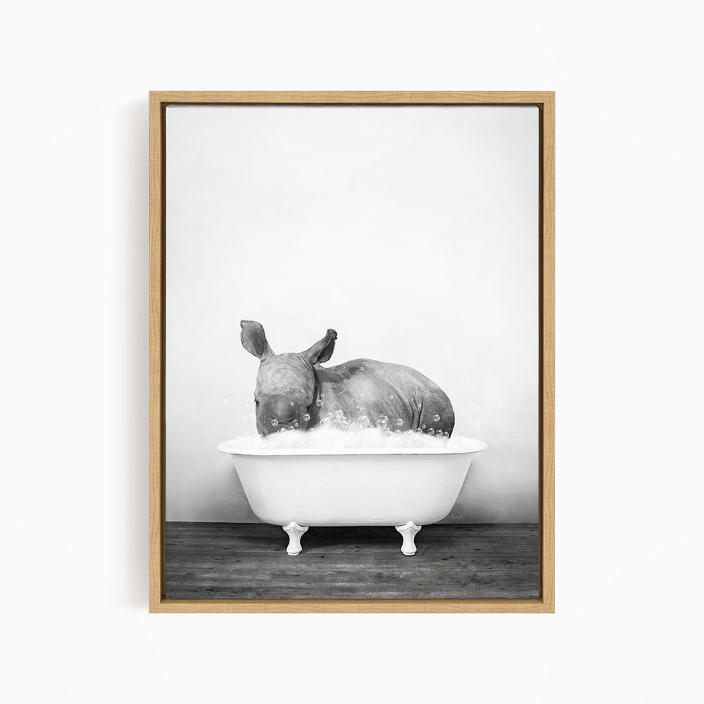 A rhinoceros is sitting in a bathtub filled with water, creating a whimsical and playful scene.