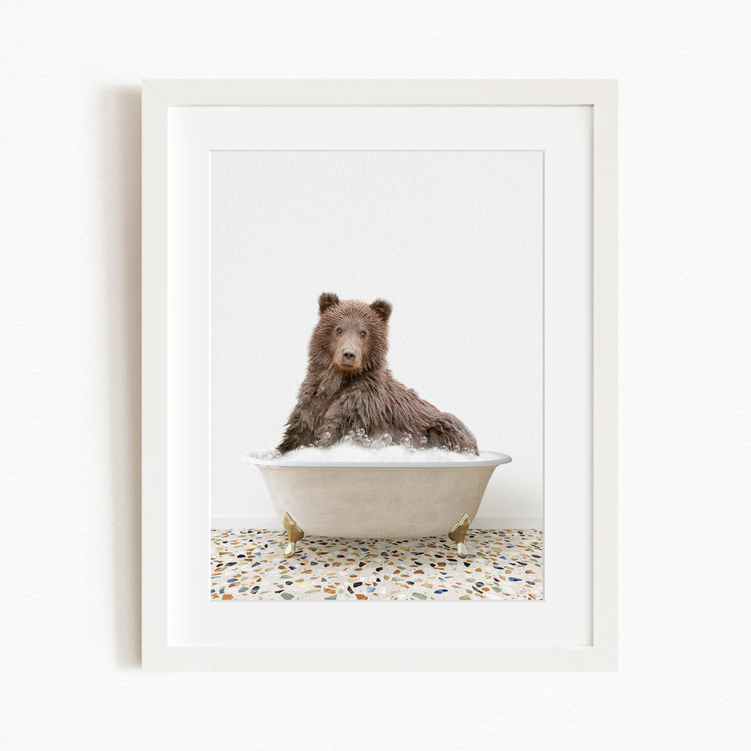 A brown bear sitting in a white bathtub filled with water, with a tiled floor in the background.
