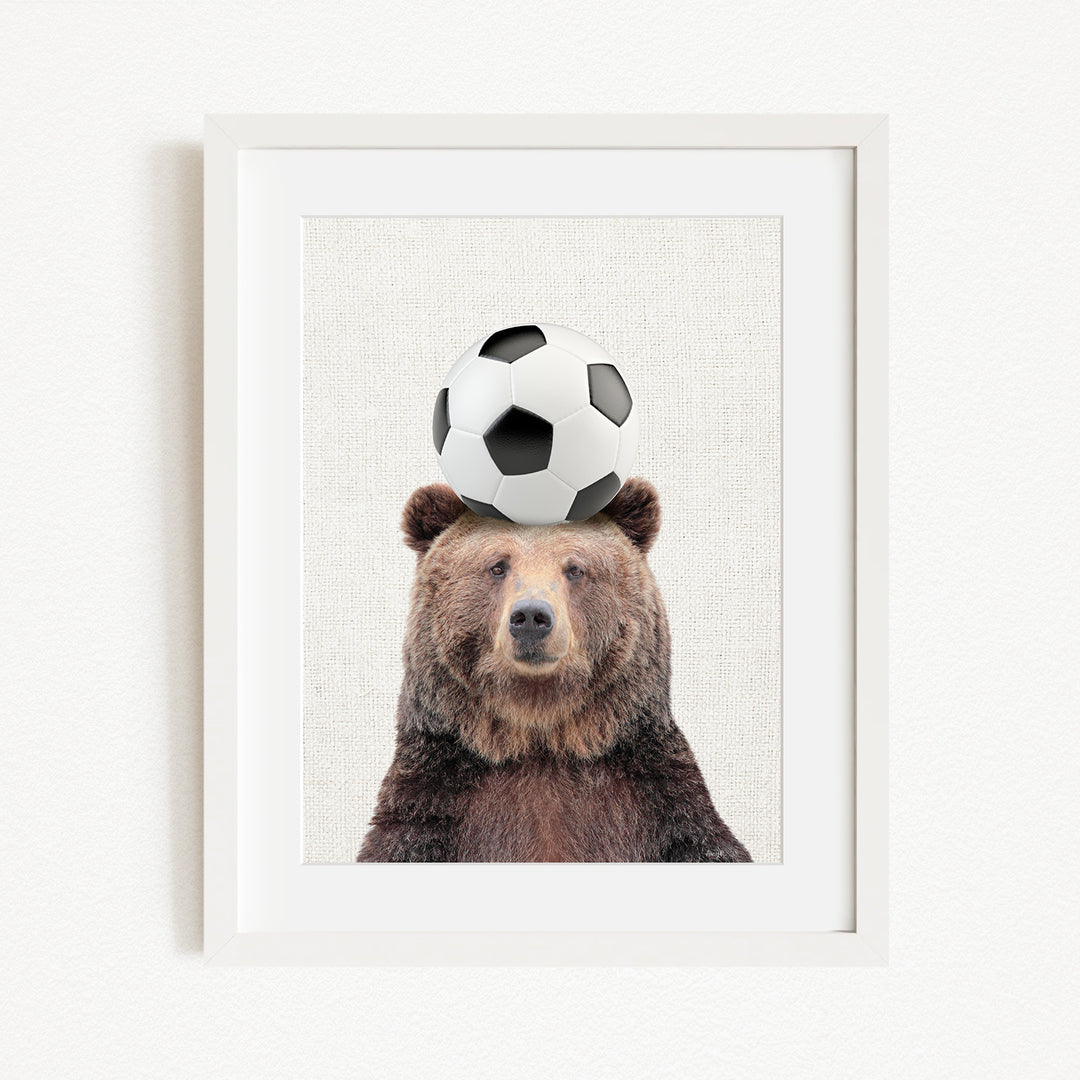 A brown bear balancing a soccer ball on its head.