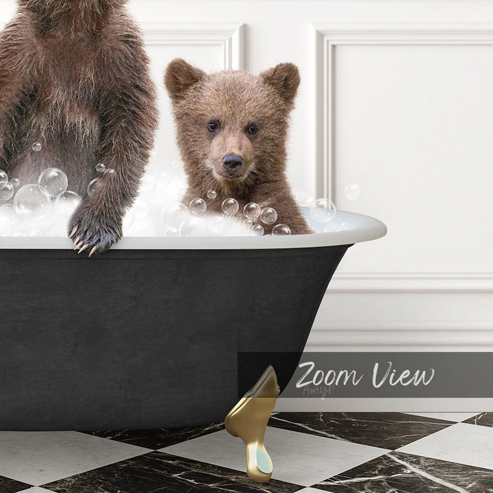 A young bear cub sitting in a bathtub filled with bubbles, with a black bathtub and a gold bathtub leg visible.