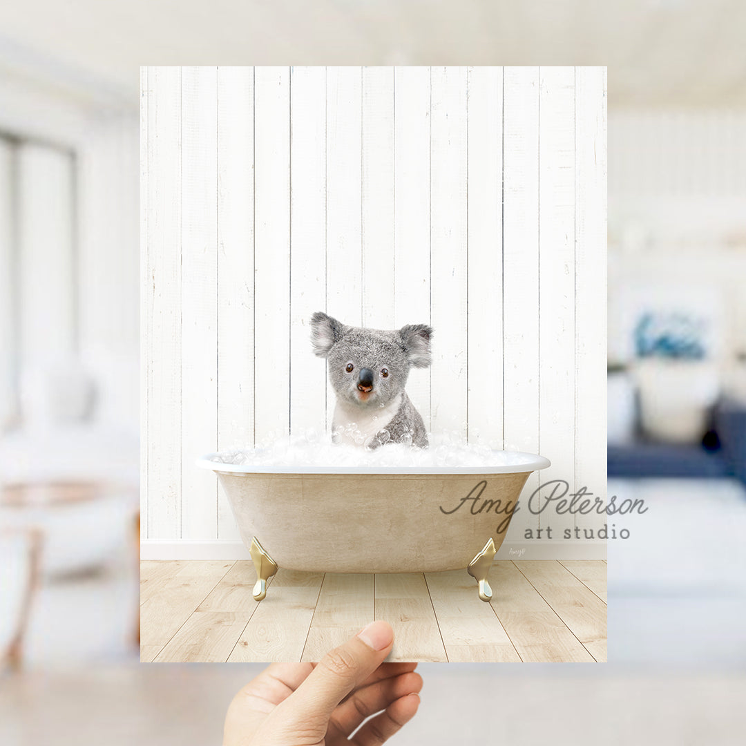 a hand holding a photo of a koala in a bathtub