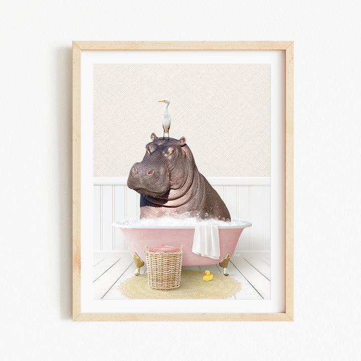 A framed image depicting a hippopotamus sitting in a pink bathtub, with a bird perched on its head.