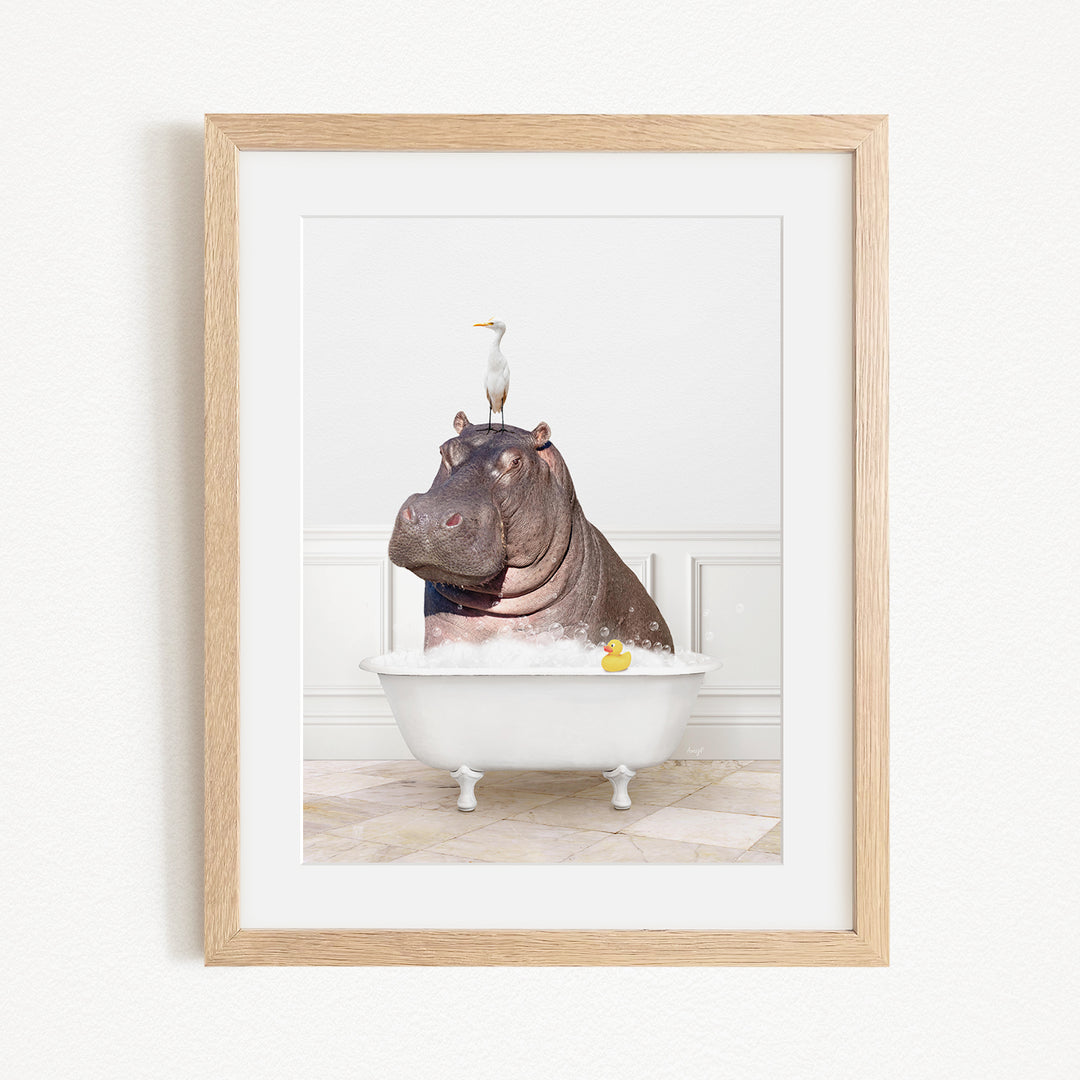 A framed image depicting a hippopotamus sitting in a bathtub, with a seagull perched on its head.