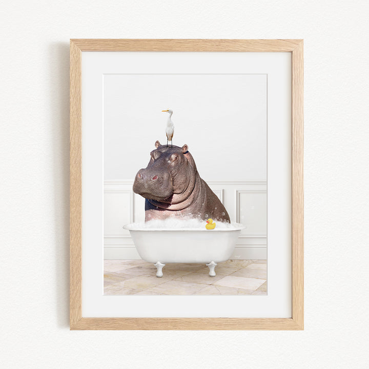 A framed image depicting a hippopotamus sitting in a bathtub, with a seagull perched on its head.