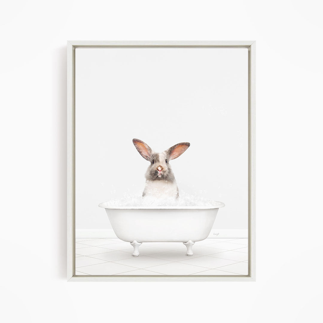 A white rabbit sitting in a white bathtub filled with water, looking directly at the camera.