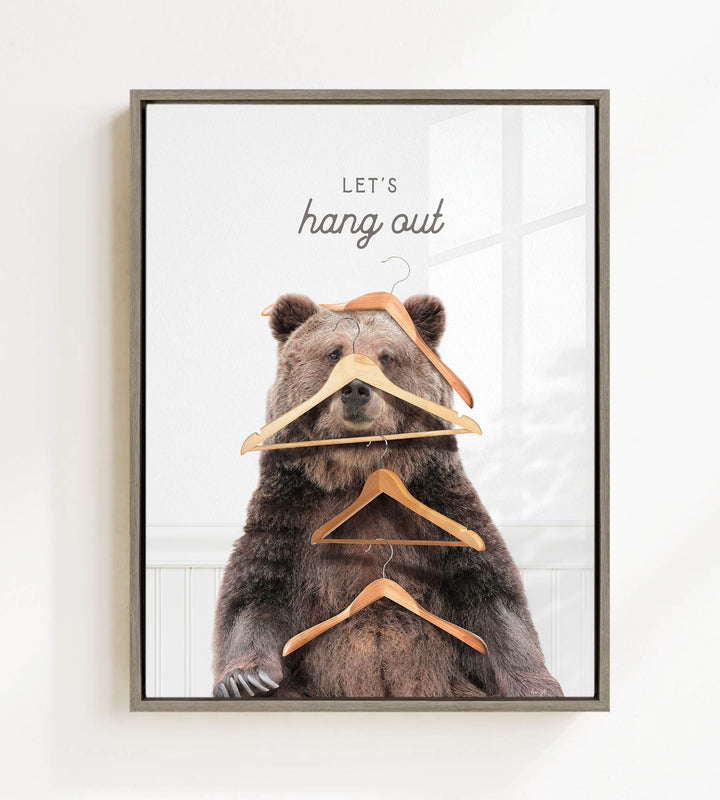 A framed image of a bear sitting on a shelf with multiple wooden hangers hanging from its head and shoulders, creating a humorous and whimsical scene.