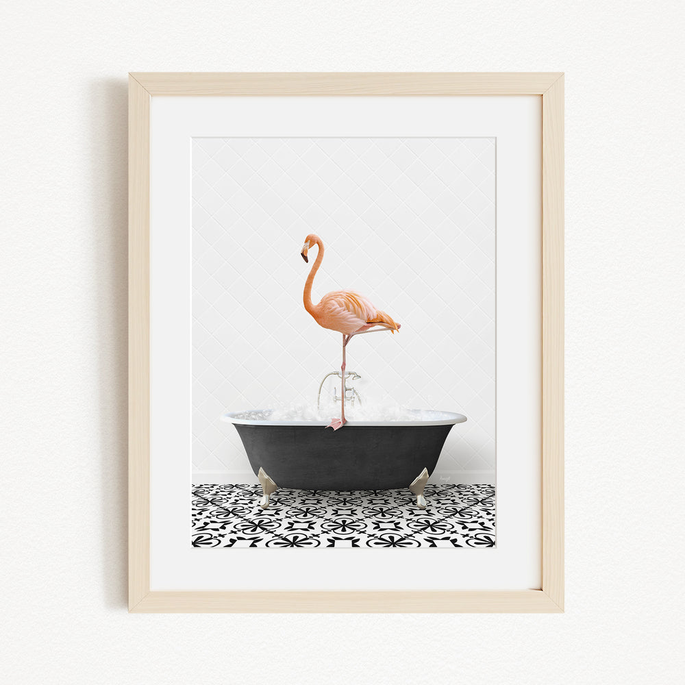 A framed image of a flamingo standing on one leg in a bathtub filled with water.